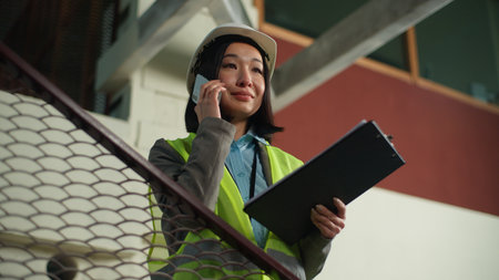 businesswoman talking mobile phone checking blueprint building builder project plan business woman female engineer cheerful girl speaking smartphone contractor architectの写真素材