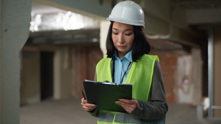 Nervous Asian Korean Japanese woman builder checking documents problem mistake building plan project...