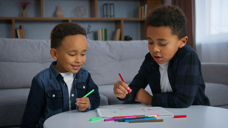 Two African American boys drawing talking enjoying spending time together ethnic family kids sons siblings children draw sketches with colorful markers felt-tip pens talk weekend art game childhoodの写真素材