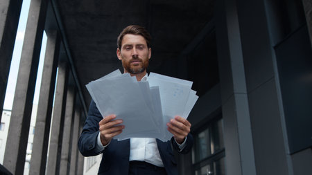 Successful happy Caucasian mature business man holding papers walking in city busy with work report contract middle-aged businessman executive entrepreneur male with documents paperwork leaving officeの写真素材