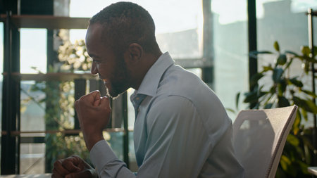 Happy African American businessman winning in sunny office. Male business man reading good news, excited winner, entrepreneur, project deal, achieve goal, success at office, celebrating.の写真素材
