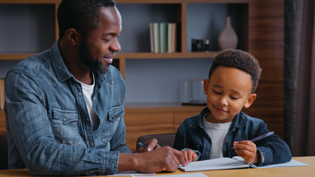 African American family clever father help son writing letters write homework man teacher tutor teaching little ethnic boy kid child pupil preparing to school dad distant busy elementary educationの写真素材