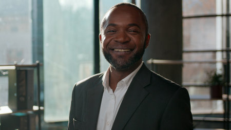 Portrait carefree African American business man look cheerful joy smiling happy looking at camera businessman mature middle-aged male executive joyful worker inspired agent in office in sun sunbeamsの写真素材