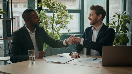 Two happy diverse business men team contract signing shaking hands teamwork cooperation handshaking multiracial businessmen Caucasian man and African American coworkers agreement partnership in officeの写真素材