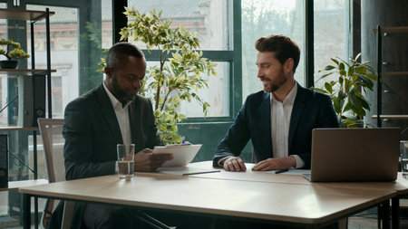 Multiethnic businessmen in office signing contract investment deal business team two diverse ethnic men teamwork busy development Caucasian African American male entrepreneurs sign document papersの写真素材