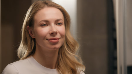 Caucasian woman in bathroom applying lipstick makeup cosmetic preparation happy beautiful blond young female girl model look mirror apply lips balm getting ready morning visage beauty routineの写真素材