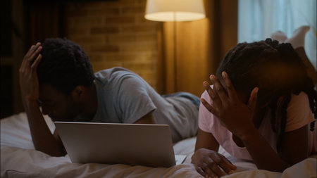 African American family argument watch laptop frustrated quarrel bad connection ethnic couple girlfriend boyfriend arguing conflict computer online sport game match at home bedroom eveningの写真素材