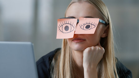 Tired Caucasian business woman pretending working laptop with sticky notes with drawing eyes on glasses businesswoman nap sleepy female girl pretend work in office sleeping falling unmotivated managerの写真素材