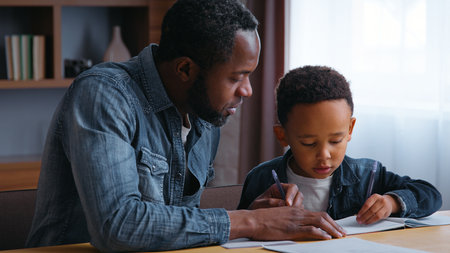 African American family dad assists son with learning teamwork lovely schoolboy with father writing homework at home child kid boy with parent tutor tutoring distant education concentration studyの写真素材