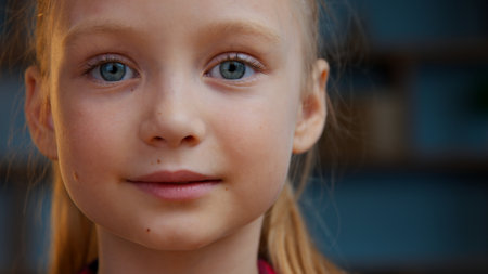 Portrait Caucasian calm beautiful adorable adopted child girl kid smiling looking at camera in evening home cute baby daughter carefree look face smile happy in apartment healthy children headshotの写真素材