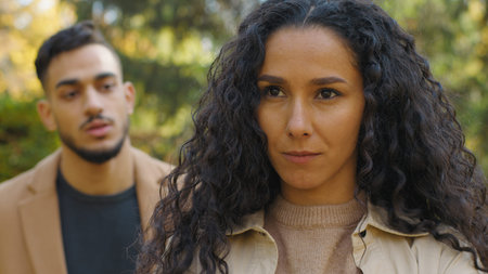 Hispanic couple quarrel in autumn park close-up offended woman ignoring angry man yelling talking...