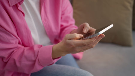 Unrecognizable Caucasian woman at home sitting couch typing mobile phone chatting cellphone female girl influencer user browsing smartphone app social media internet online shopping texting indoorsの写真素材