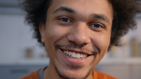 Happy African American man close up portrait smiling toothy looking at camera home guy healthy skin...