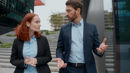 Caucasian business woman man partners talking discussing project walking in city middle-aged...