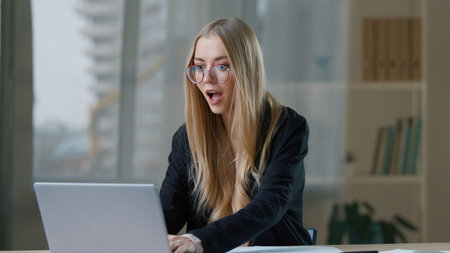 Successful Caucasian business woman winning with laptop reading good news in office businesswoman rejoice online win in workplace company job offer opportunity female happy girl manager achieve gladの写真素材