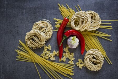 Raw Italian pasta on dark grey table. Ingredients top view photo.の写真素材