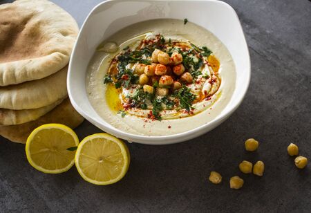 Plate of fresh homemade hummus with pita bread on the table. Authentic food of Middle East. Healthy eating concept. Vegan balanced dish. Traditional meal of Israel.の写真素材