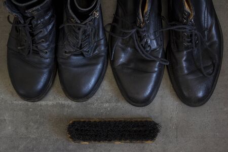 Black leather retro boots and wooden shoe brush on grey background with copy space.の写真素材