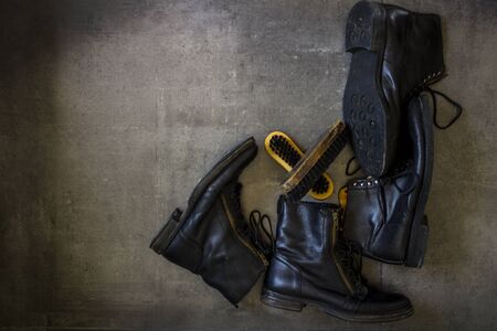 Black leather retro boots and wooden shoe brush on grey background with copy space.の写真素材