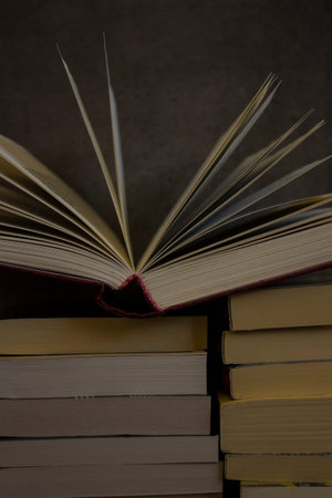 Stack of old books on dark grey background. Open book pages. Library photo.