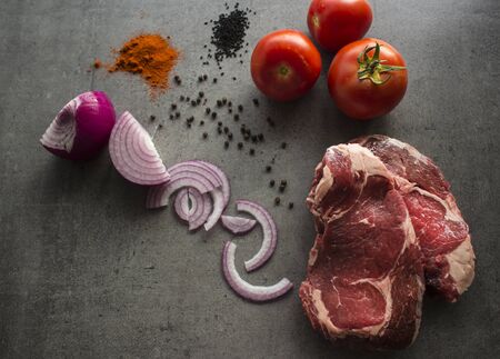 Raw beef steaks, fresh vegetables, spices and herbs on a table. Fresh ingredients top view photo.の写真素材