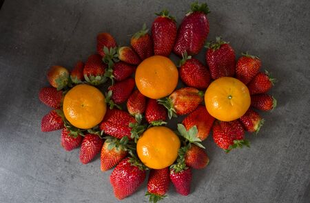 Strawberries and oranges on dark grey background with copy space. Fruits top view photo.の写真素材