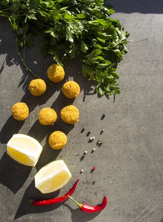 Falafel - authentic food of Israel. Fresh ingredients top view: plate of falafels, pita bread, parsley, harissa sauce, lemon, parsley and red pepper.Â  Dark grey background with copy space.Â の写真素材