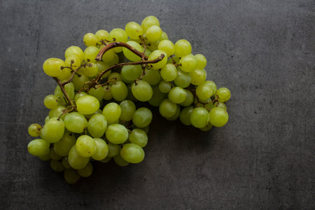 Green grapes close up photo. Juicy fruits top view. Dark grey background with copy space.