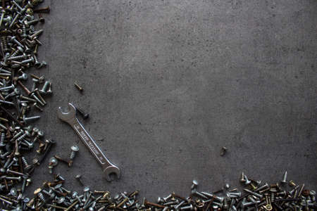 Old bolts and nuts on dark grey concrete background. Frame or border. Textured background with copy space.の写真素材