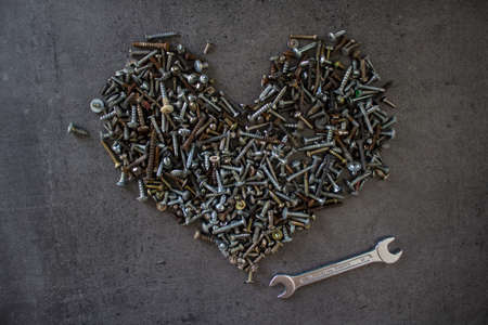 Heart shape made of old bolts. Dark grey textured background with copy space. Handyman serviceの写真素材