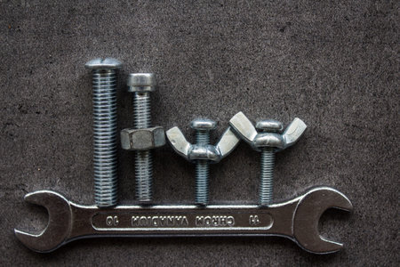 Bolts family. Wrench tool, old nuts and bolts of different sizes top view photo. Grey textured...