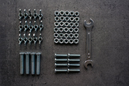 Wrench tool, old nuts and bolts of different sizes top view photo. Grey textured concrete background...