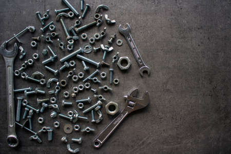 Wrench tool, old nuts and bolts of different sizes top view photo. Grey textured concrete background with copy space. Handyman tools close up picture. Home renovation concept.の写真素材