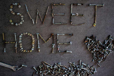 Home sweet home.  Old bolts of different sizes on dark grey textured background.  Top view photo. Industrial style.の写真素材
