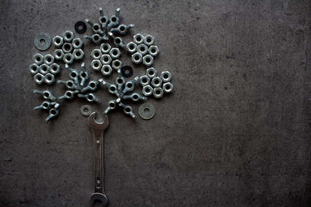 Tree and heart shape made of bolts on dark grey ttextured background with copy space. Handyman tools close up photo.の写真素材