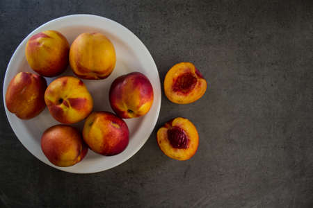 Fresh nectarines close up photo. Water drops on juicy summer fruits. Dark grey background. Healthy eating concept.の写真素材