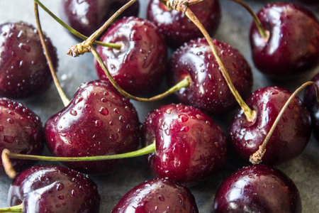 Juicy cherry close up photo. Water drops on fresh berries. Dark grey textured background. Healthy...