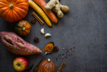 Fresh autumn vegetables and spices on dark grey textured background. Top view photo of carrots and squashes.の写真素材