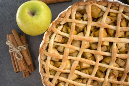 Apple pie with lattice decoration. Homemade dessert pie top view photo. Grey background.の写真素材