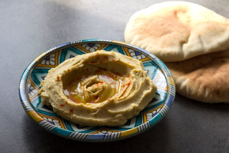 Hummus on a colorful plate on gray table. Traditional food of Middle East. Dark background with copy...