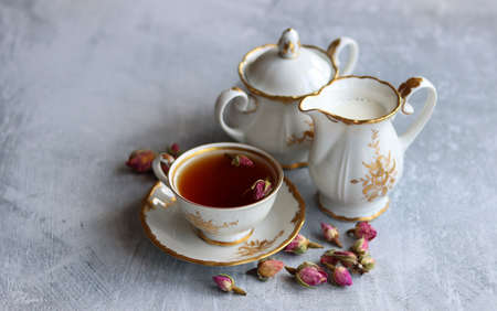 Tea with roses close up photo. Herbal tea in a small white ceramic cup on a table. Light grey background with copy space.の写真素材