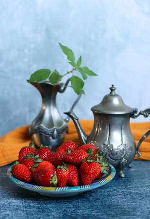 Still life with retro styled objects and juicy strawberry. Close up photo of organic fruit on a plate.の写真素材