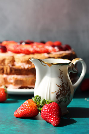 Still life with cake and retro styled objects on a table. Vintage cup with black tea, strawberry...