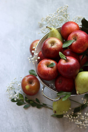 Red apples and pears in a metal bowl on a light backgroundの写真素材