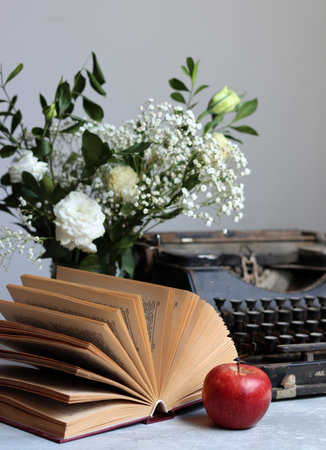 Vintage typewriter, books and a red apple on the tableの写真素材