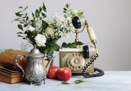 Vintage telephone, books, apples and flowers on the table.の写真素材
