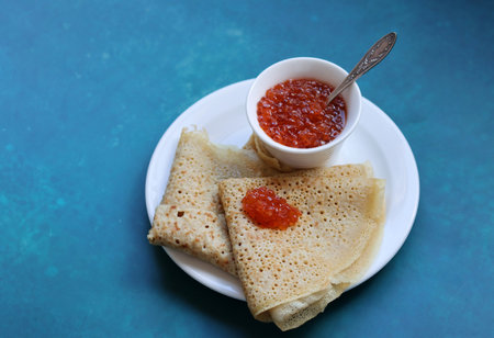 pancakes with red caviar on a plate on a blue backgroundの写真素材