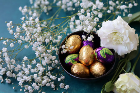 Foil wrapped Easter chocolate eggs in a glass bowl. Easter celebration concept. Colorful still life with sweets. Textured background with copy space. Easter greeting card.の写真素材