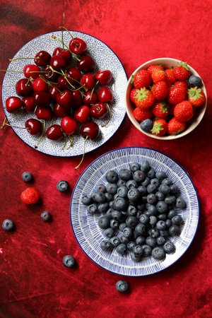 Berries on a plate on a red background. Summer berries.の写真素材