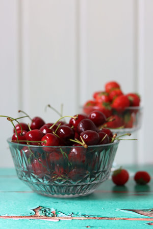 Cherries in a glass bowl on a turquoise tableの写真素材